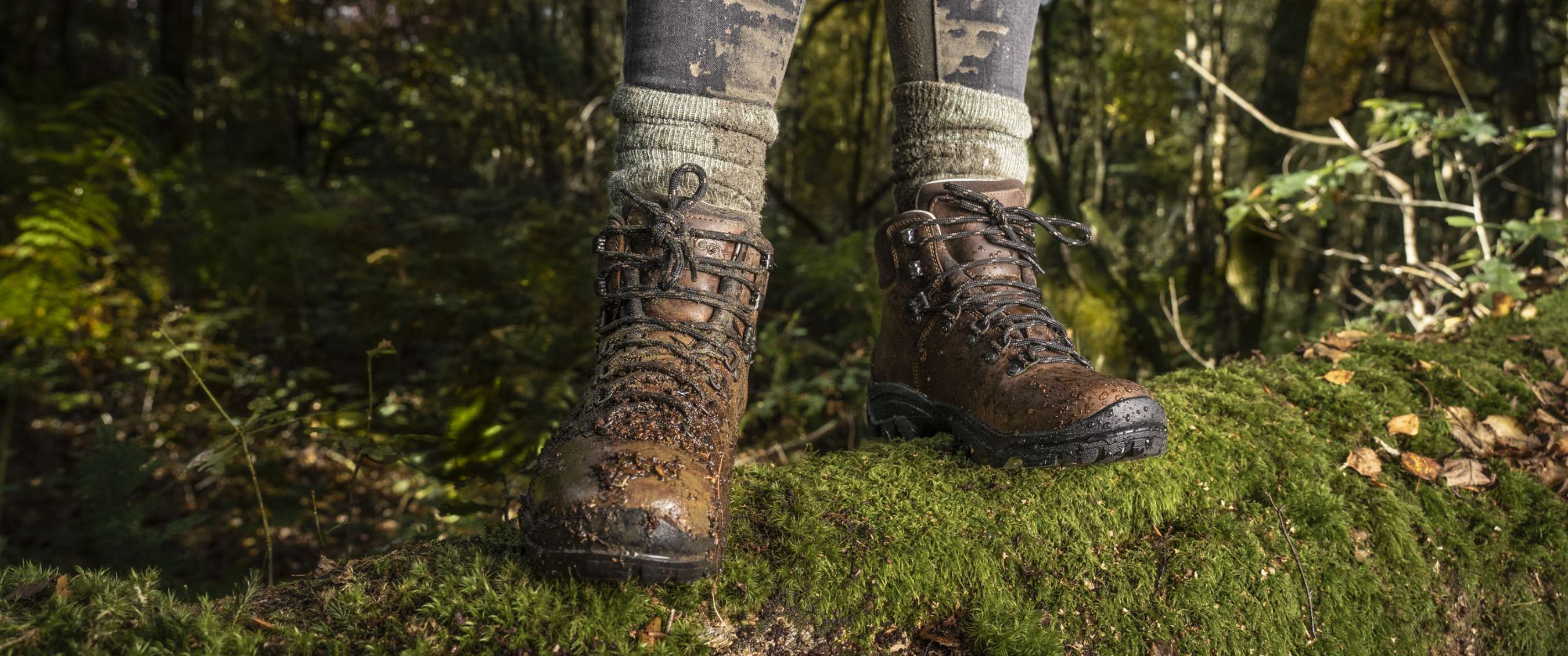 Two brown boots worn by someone perching atop a mossy branch