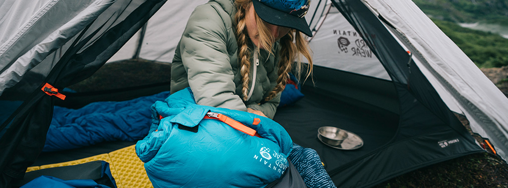 A lady packing her sleeping bag in its cover