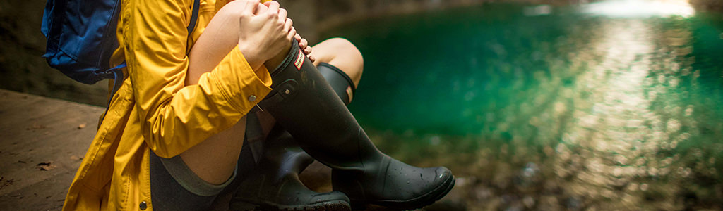 A woman wearing wellies by a body of water 