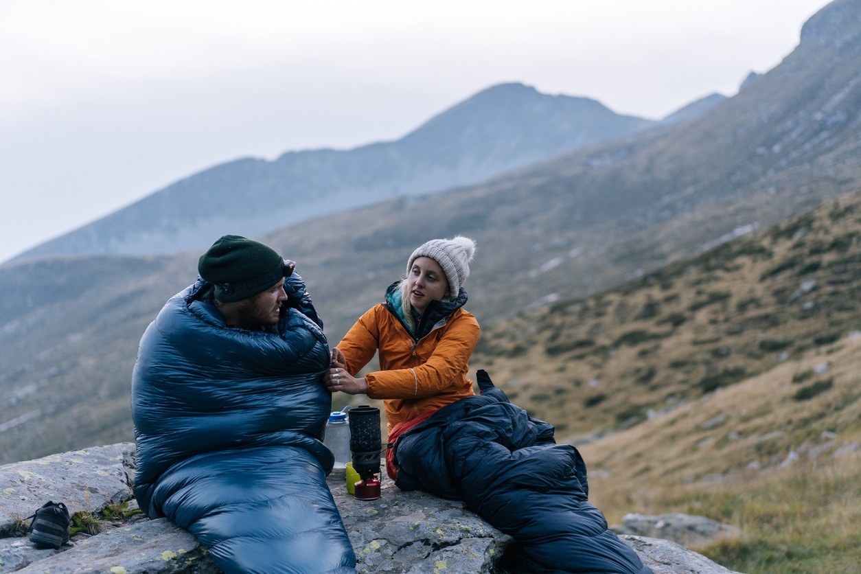 Two campers in their sleeping bags outside
