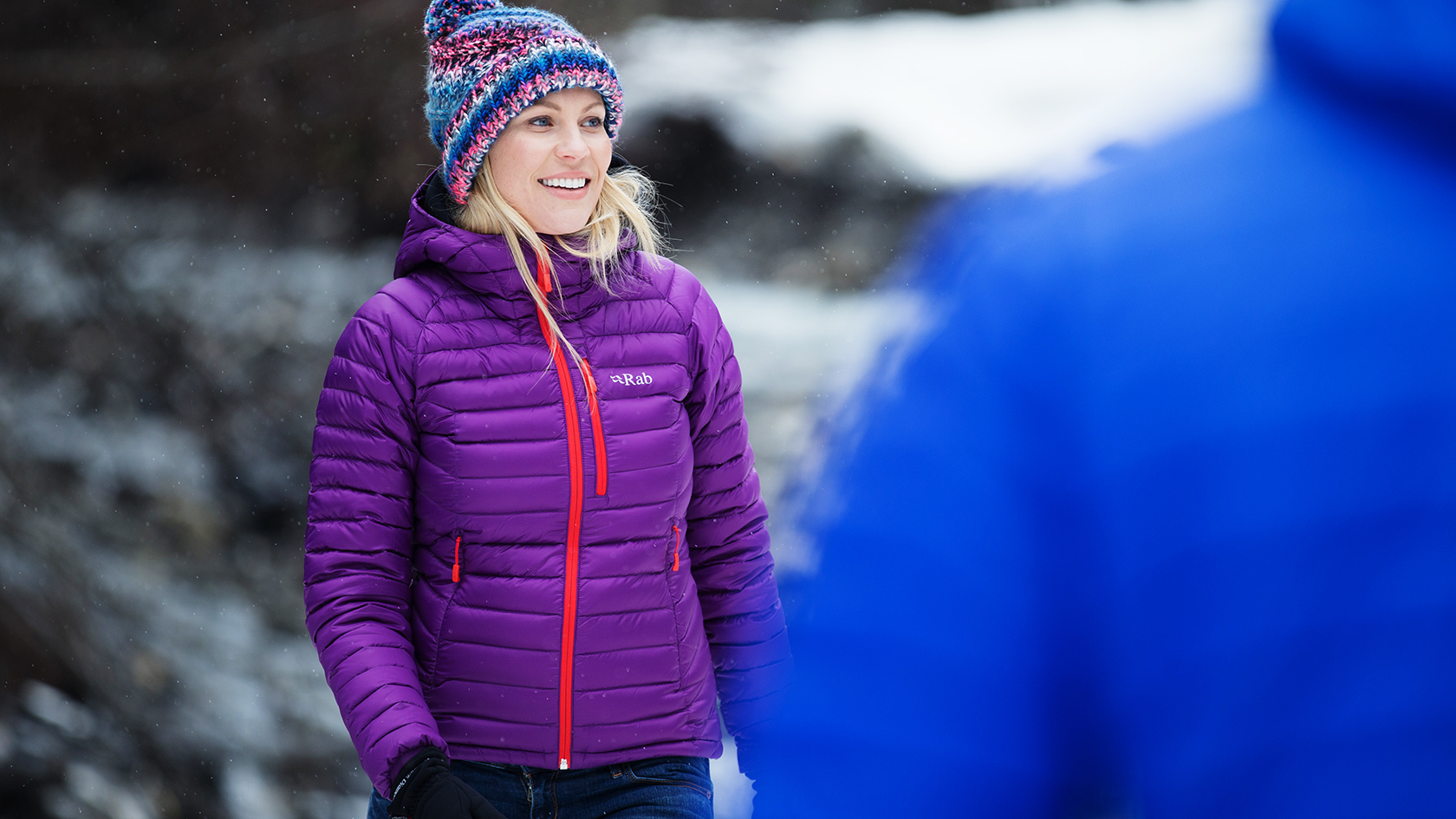 A woman wearing a purple rab down jacket and a wooly hat 