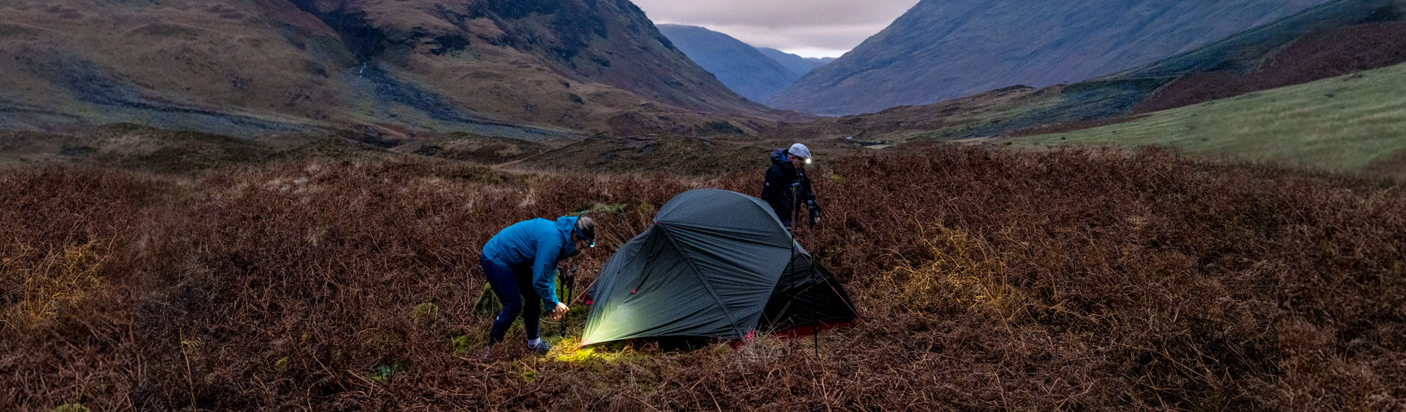 People pitching their tent wearing head torches